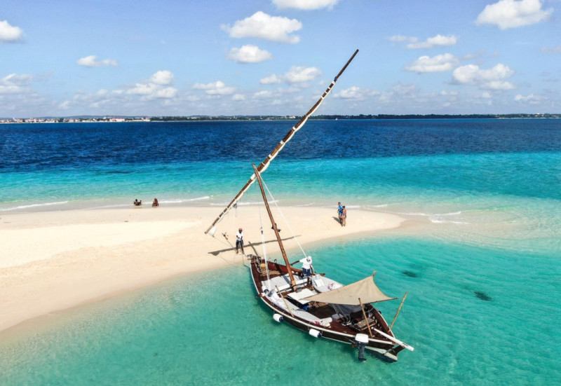 White beach surrounded by clear blue water and a boat in it