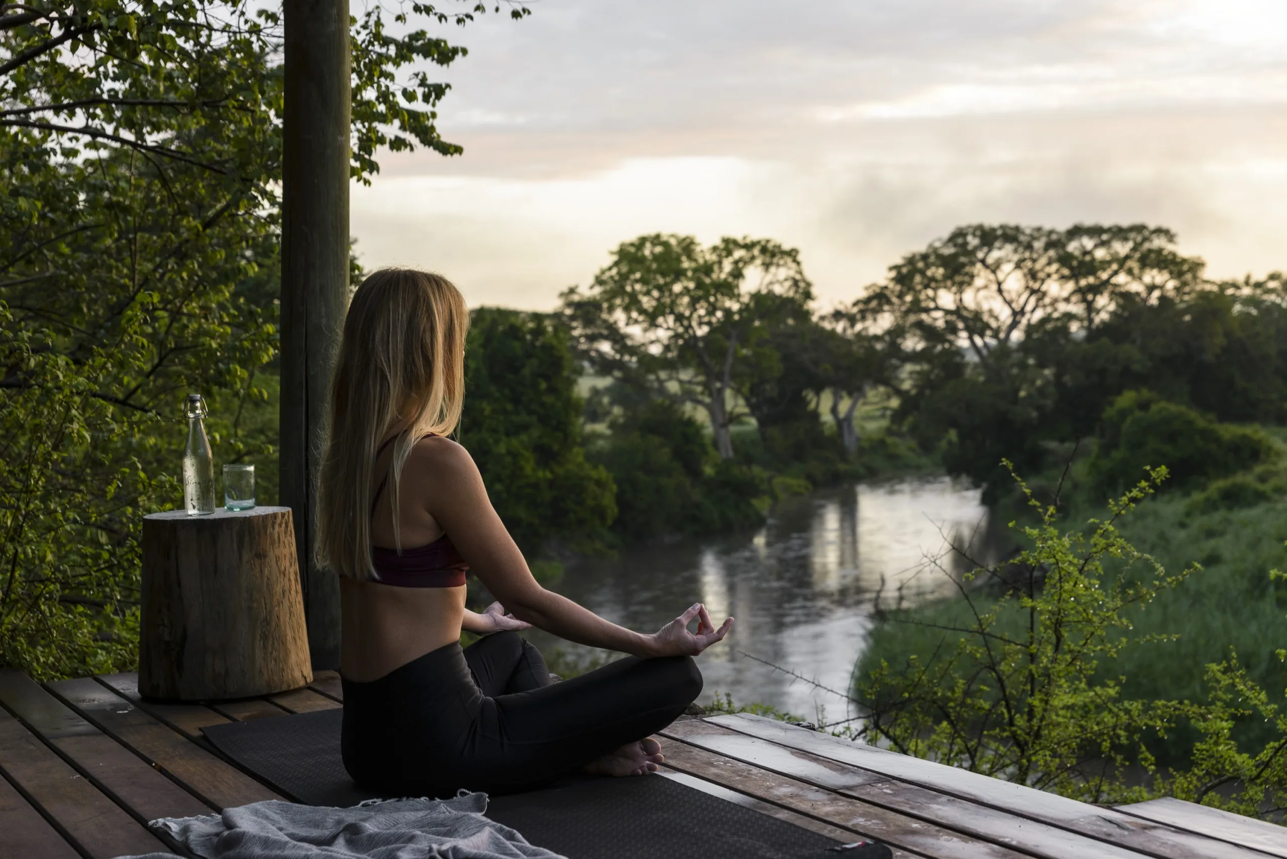 Woman enjoying a peaceful moment by the water during an exclusive safari experience in Africa