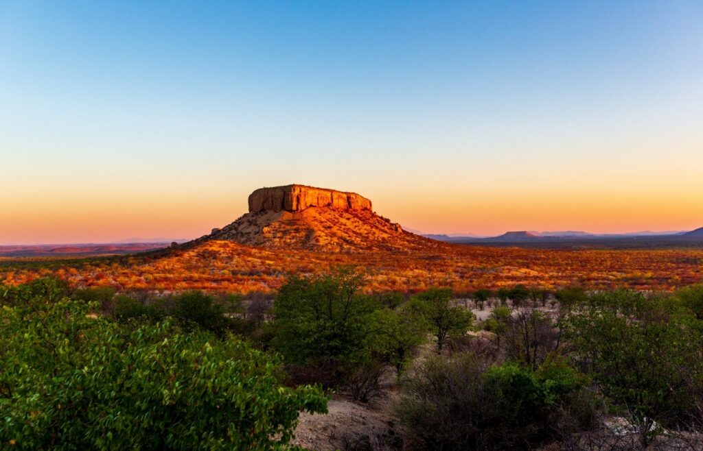 Waterberg Plateau Namibia with sunlit mountain and trees on the ground in front