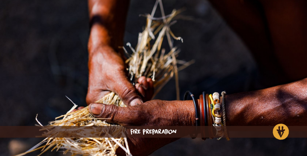 Two black hands with bracelets hold dry grass.